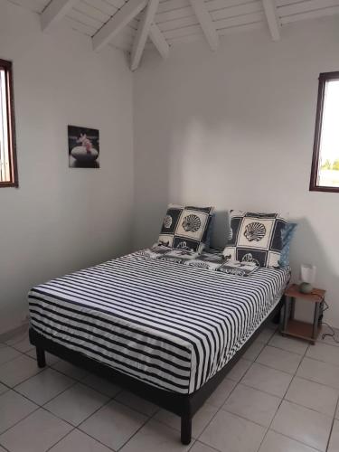 a bed in a room with a black and white striped mattress at Haut de villa paisible pour 4 personnes in Le Moule
