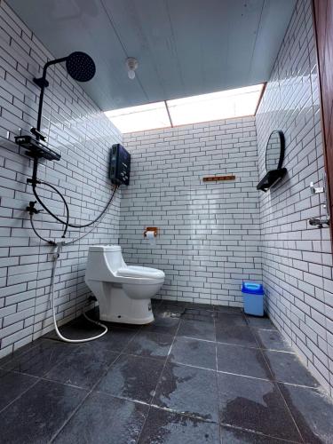 a bathroom with a shower and a toilet in a room at Pijar Jingga Cabin in Diyeng
