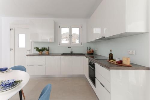 a white kitchen with a sink and a table at Villa Sun in Naxos Chora