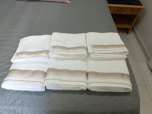 four white towels are stacked on a bed at Edícula 55m2, aceita pequenos pets in Foz do Iguaçu
