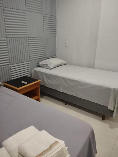 two beds in a small room with a table and a bed at Edícula 55m2, aceita pequenos pets in Foz do Iguaçu