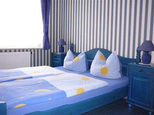 a bedroom with a blue bed with yellow and white pillows at Rezydencja Nad Jeziorem Łebsko in Łeba