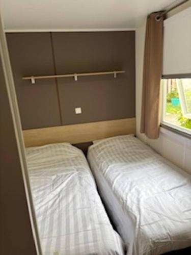 two beds in a small room with a window at Mobilhome 642 3 chambres Siblu La Réserve in Gastes