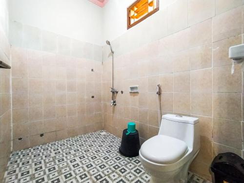 a bathroom with a toilet and a tiled floor at Famoris Cottages in Tetebatu