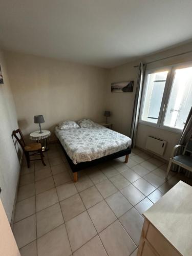 Maison de vacances في Dolus-d'Oléron: غرفة نوم بها سرير وطاولة ونافذتان