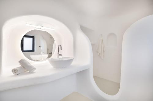 a white bathroom with a sink and a mirror at Princess Villas Oasis Mykonos in Kalafatis