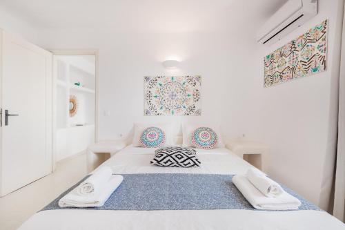 a white bedroom with a bed with towels on it at Princess Villas Oasis Mykonos in Kalafatis