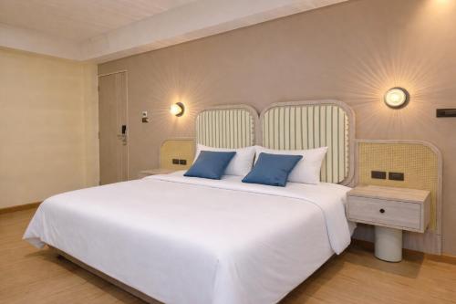 a bedroom with a large white bed with blue pillows at Ranana Bangkok in Bangkok