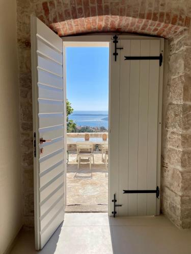 an open door to a patio with a view of the ocean at Luxury stone house with infinity pool in Herceg-Novi