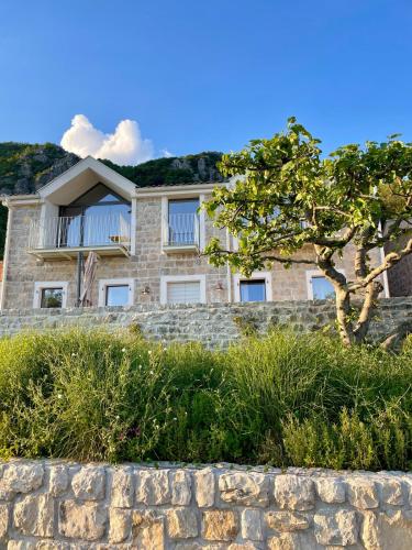 a house on a hill with a stone wall at Luxury stone house with infinity pool in Herceg-Novi