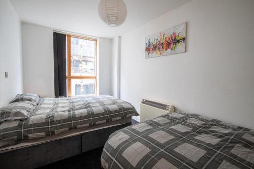 a bedroom with two beds and a window at Manchester City Square in Manchester