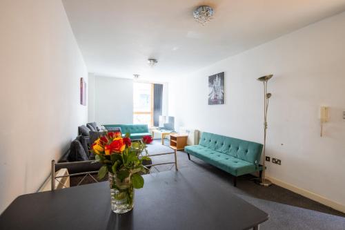 a living room with a vase of flowers on a table at Manchester City Square in Manchester