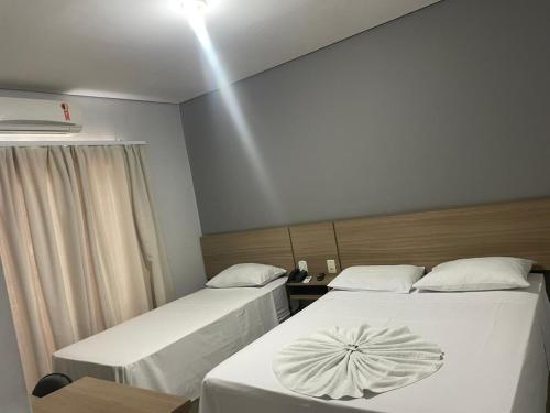 a room with two beds and a light on the ceiling at Hotel Comodoro in Vilhena