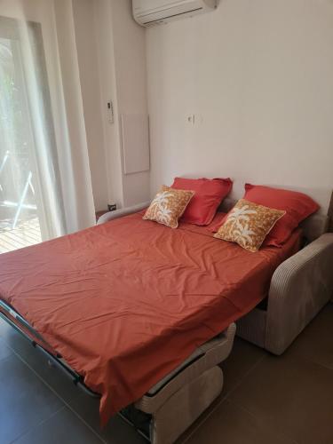 a bed with red sheets and pillows in a room at Le Studio Joli in La Possession