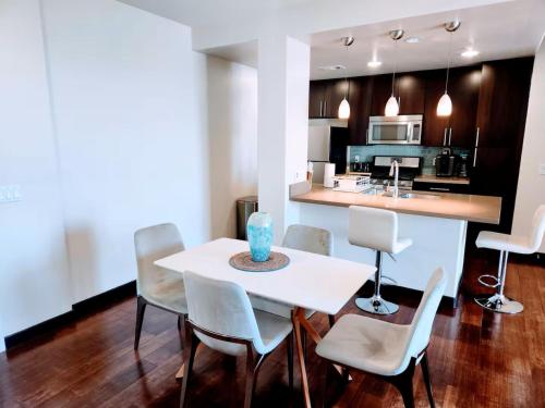 a kitchen and dining room with a white table and chairs at Hollywood Panoramic Views, Pool, Gym & Free parking! in Los Angeles