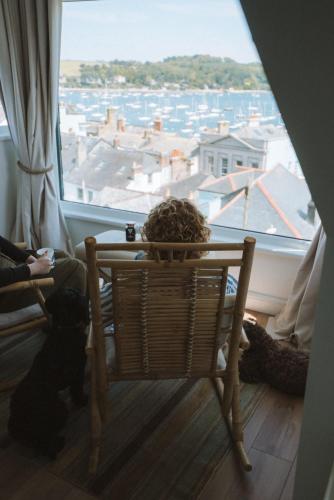 a person sitting on a couch in front of a window at Stunning High Street Townhouse With Sea Views & Parking at 'Tide View Townhouse' in Falmouth