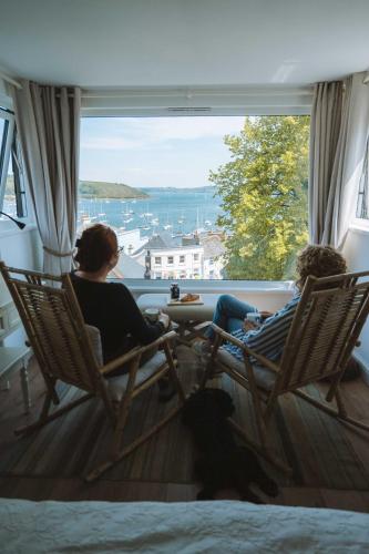 two people sitting in chairs looking out of a window at Stunning High Street Townhouse With Sea Views & Parking at 'Tide View Townhouse' in Falmouth