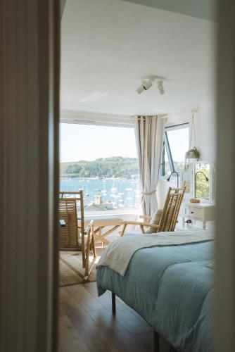 a bedroom with a bed and chairs and a large window at Tide View Townhouse - By Rowes Retreats in Falmouth