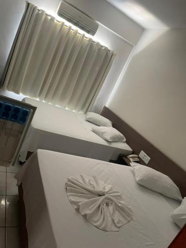 a room with two beds and a window in it at Hotel Comodoro in Vilhena