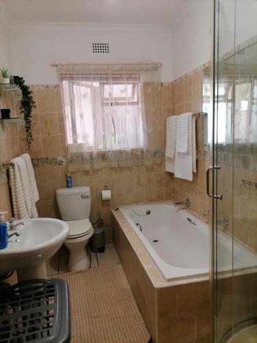 a bathroom with a tub and a toilet and a sink at Mimosa House Twin Room in Brackenfell