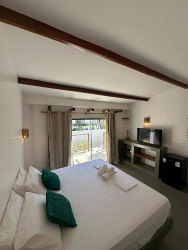 a bedroom with a large white bed with green pillows at BaleiaLofts Kite Village in Itapipoca