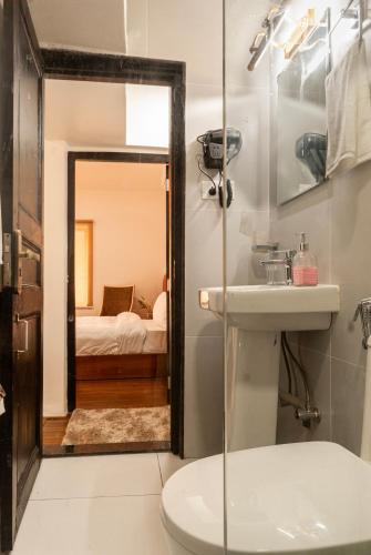 a bathroom with a sink and a toilet and a bedroom at The Hush Nepal in Kathmandu