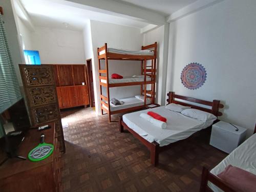 a bedroom with a bed and a bunk bed and a shelf at Pousada Andarai in Andaraí