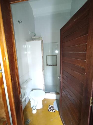 a bathroom with a toilet and a wooden door at Pousada Andarai in Andaraí
