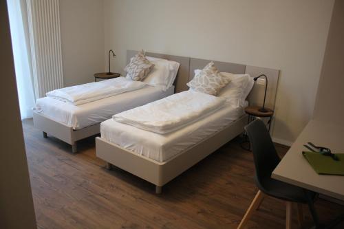 a room with two beds and a desk with a chair at Il giardino in campagna in Seren del Grappa