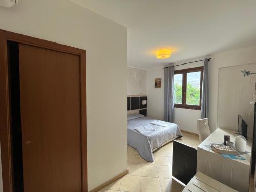 a bedroom with a bed and a desk and a window at B&B Agrodolce in San Vito lo Capo