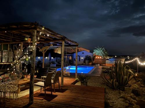 a deck with lights and a pool at night at Ruime cortijo met zwembad in Andalusië ideaal voor families & groepen 3 appartementen in Huércal-Overa