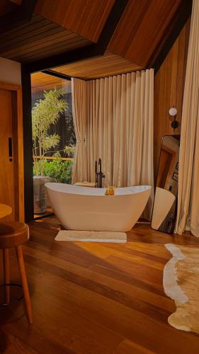 a bathroom with a white tub and a window at Chalé RIVAGI in Passa Quatro