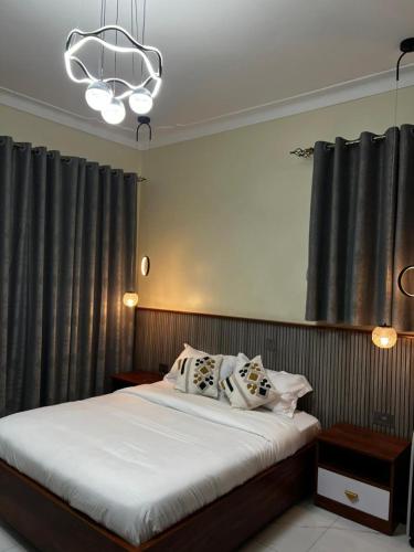 a bedroom with a bed and a chandelier at Sunset Statehouse View Residence A in Entebbe