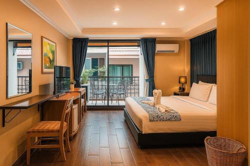 a hotel room with a bed and a desk and a balcony at the L Hua Hin in Hua Hin