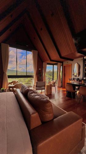 a living room with a large couch in a room with windows at Chalé RIVAGI in Passa Quatro