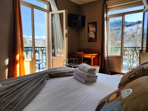a bedroom with a bed with towels on it with a balcony at Hotel Au Val Doré in La Bourboule