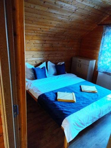 a bedroom with a blue bed in a wooden cabin at Panorama Apuseni in Beliş