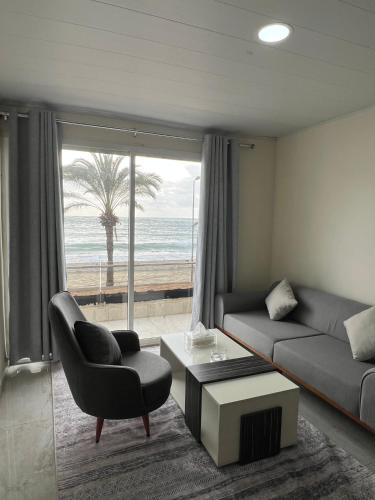 a living room with a couch and a chair and the ocean at voya hotel and suites in Soûr