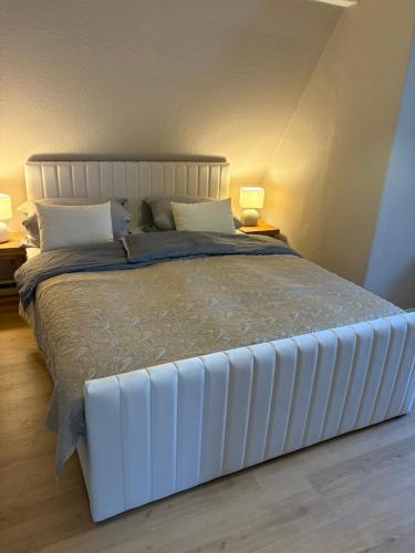 a large white bed in a bedroom with two lamps at Kutscherhaus in Uelzen