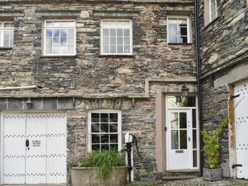 an old stone house with white doors and windows at Methera Cottage in Ambleside
