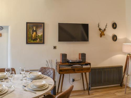 a dining room with a table and a flat screen tv at Methera Cottage in Ambleside