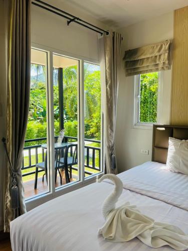 a bedroom with a bed and a balcony with a table at Koh Yao Modern Inn -SHA Plus in Ko Yao Yai