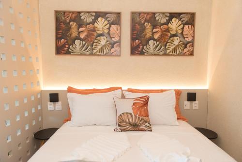 a bed with three pictures on the wall above it at Beach Class Summer in Porto De Galinhas