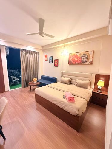 a bedroom with a large bed and a blue couch at Hazelnut -Expo India centre in Greater Noida