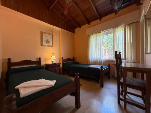 a bedroom with two beds and a table and a window at Hotel Siena Pinamar in Pinamar