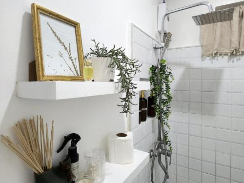 a bathroom with white tiles and plants on the wall at Soak Screen Urban Hideaway in Iloilo City