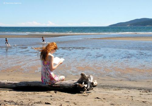 a young girl sitting on a log on the beach at Hôtel Mingan in Sept-Îles