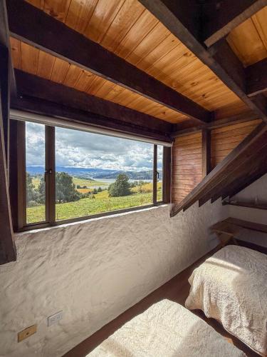 a bedroom with a large window with a view at Finca Lituania, El Sisga in Chocontá
