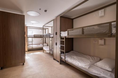 a room with three bunk beds and a hallway at Jeroom Hostel in Jerusalem