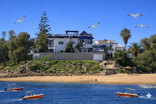 a house on the beach with boats in the water at Villa Sur La Plage in Oualidia